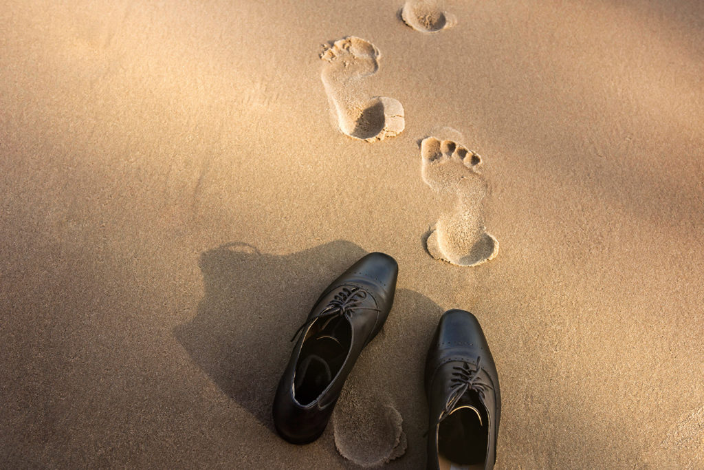 Work-Life Balance Concept, Businessman takes off his Working Oxford Shoes and leaves them on the Sand Beach for Walk into the Sea on Sunny Day. Top View