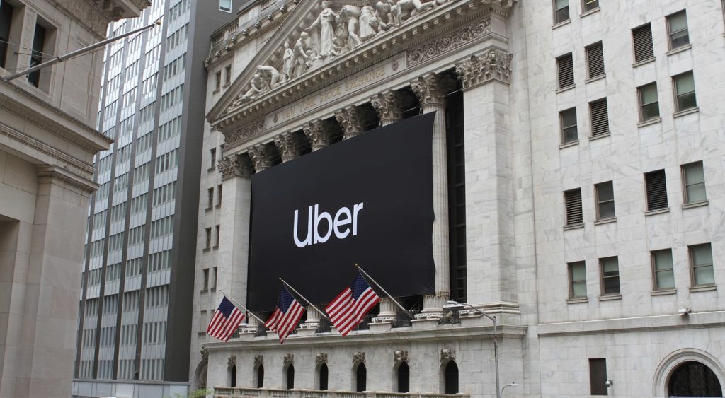 A picture the front of the New York stock exchange with and Uber sign hanging out front