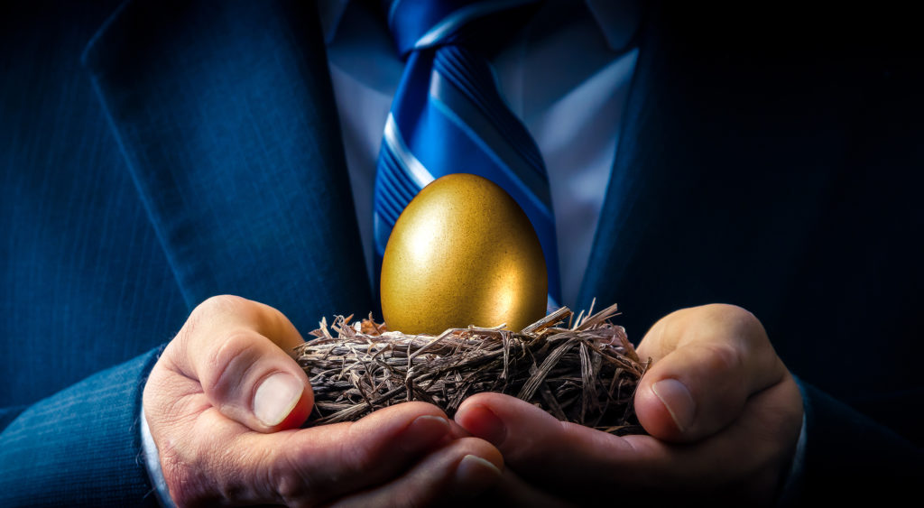 Businessman holding a nest with a golden egg